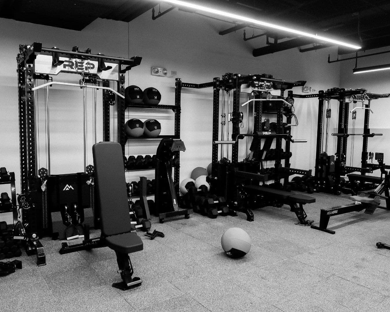 Black-and-white view of the OMNI gym floor with racks, benches and a medicine ball