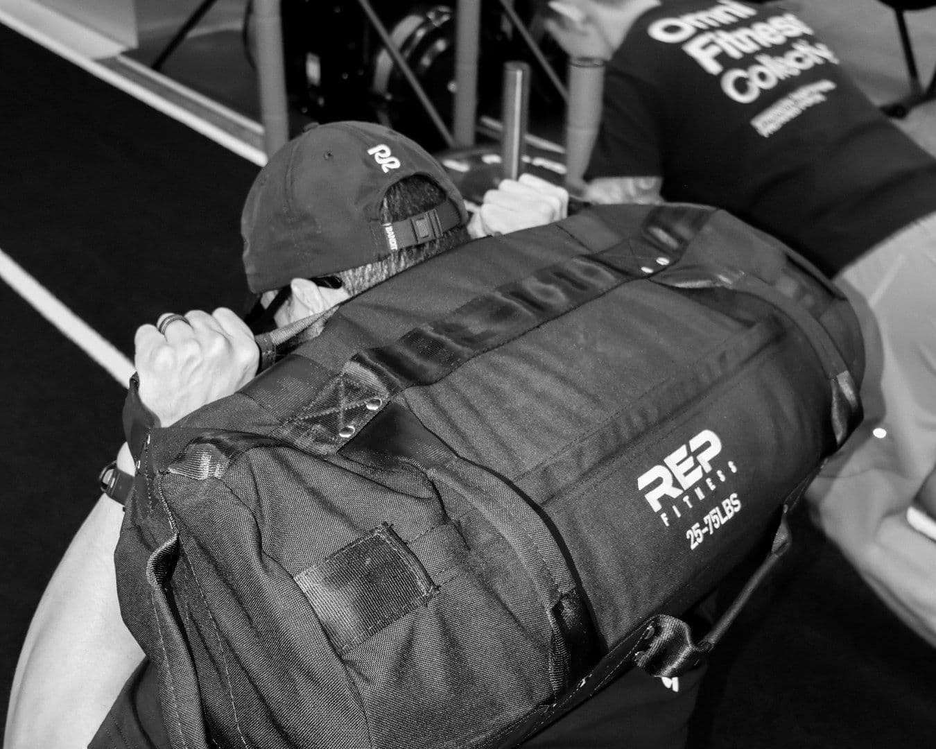 Black-and-white close-up of a member carrying an OMNI REP duffel bag